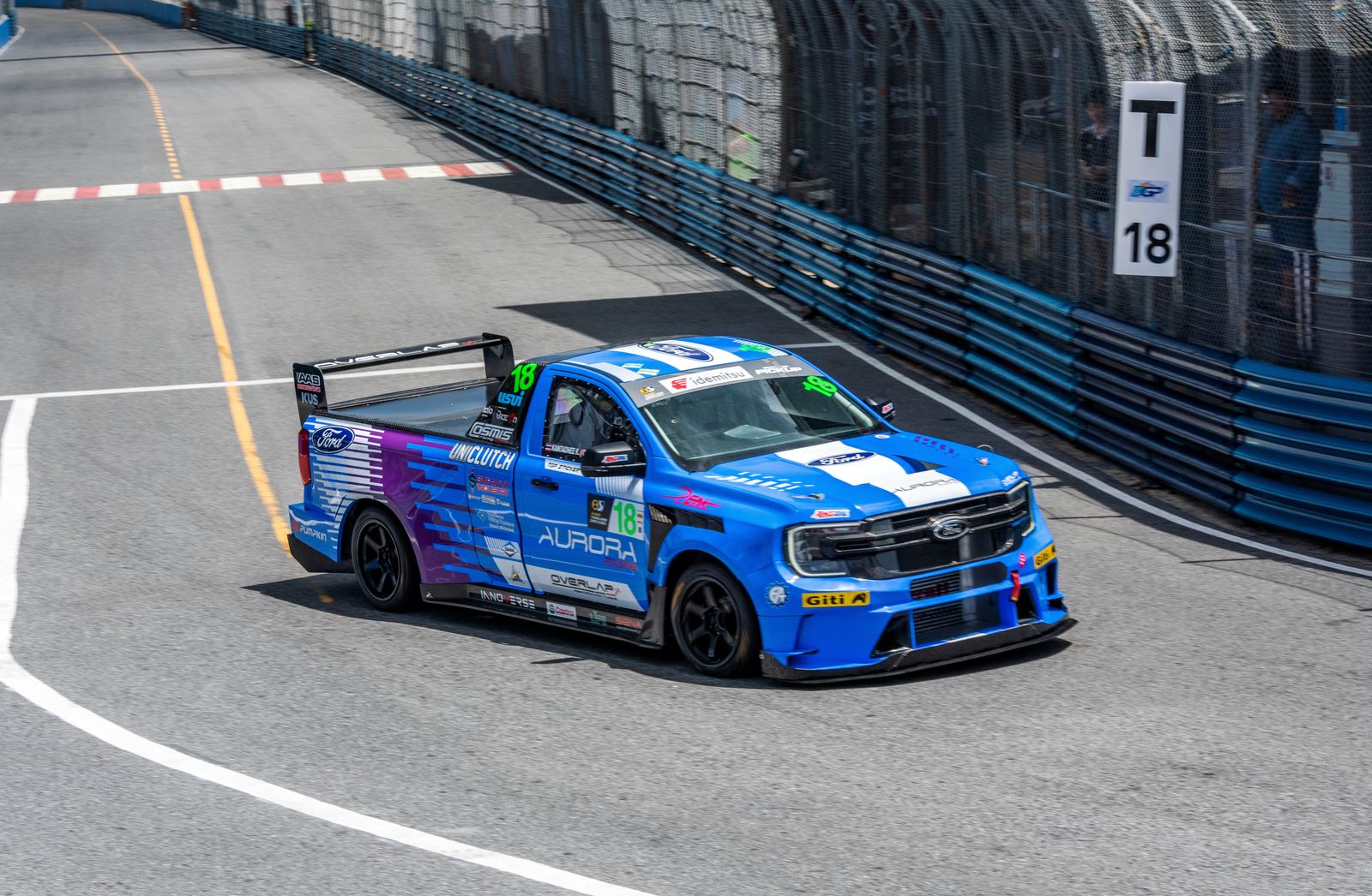 Blue number 18 Ford Ranger race truck cornering on a street circuit