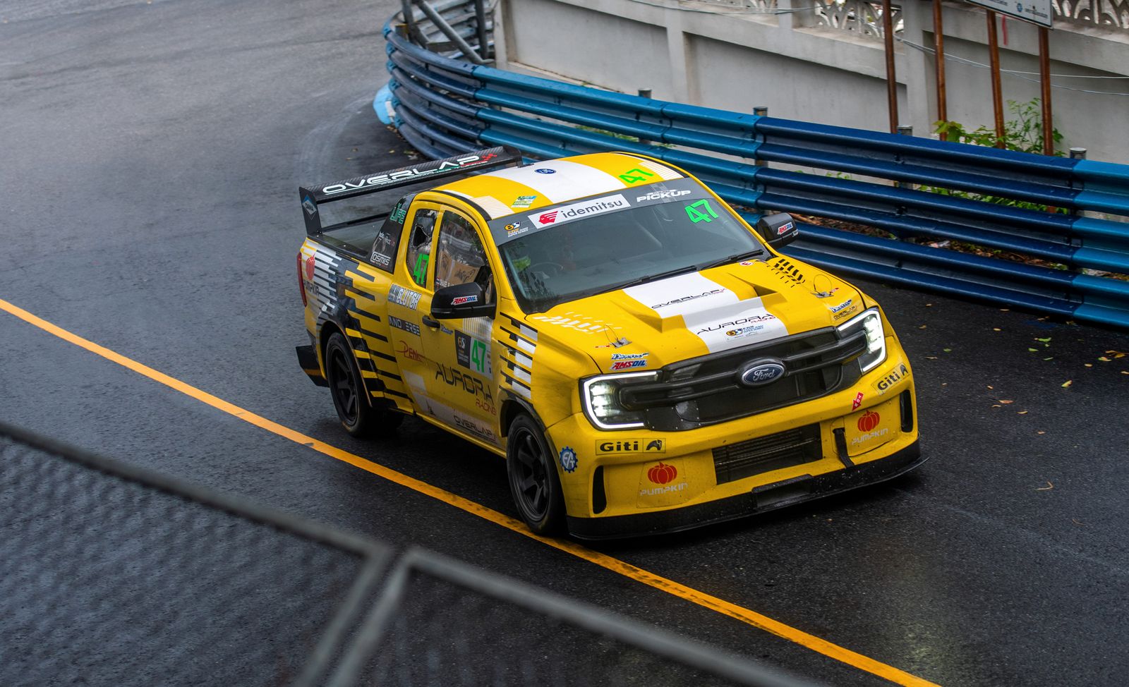 Yellow number 47 Ford Ranger race truck on a wet street circuit