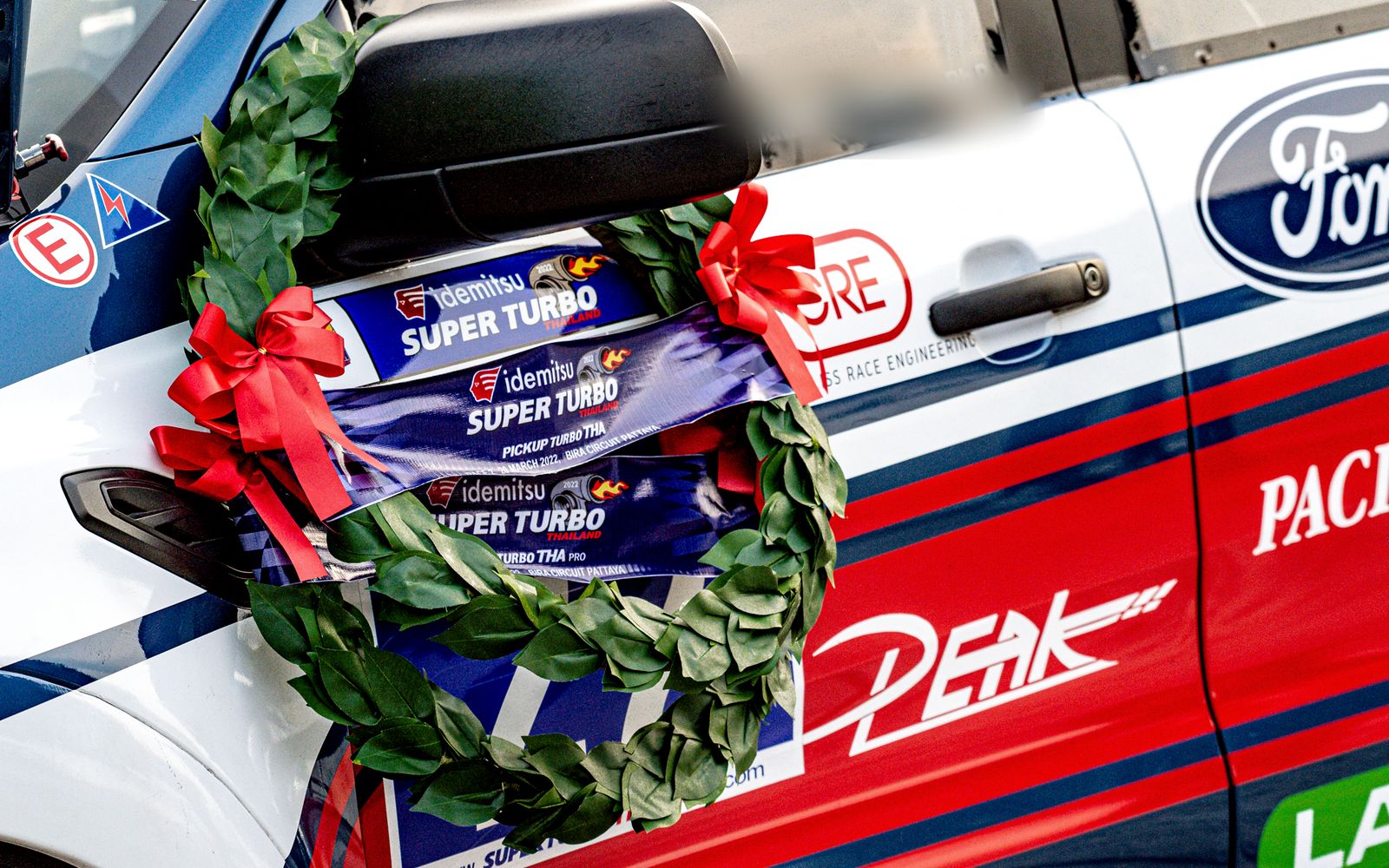 Winner's wreath on a race truck door carrying the PEAK logo